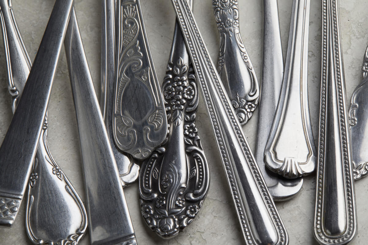 A collection of silver spoons and forks arranged neatly on a white background. 