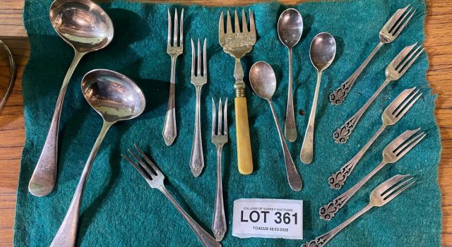 A collection of polished silverware arranged neatly on a vibrant green cloth.