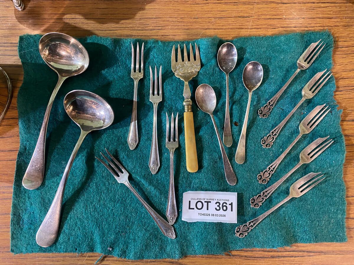 A collection of polished silverware arranged neatly on a vibrant green cloth.